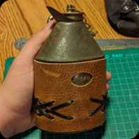 Cover for an antique screw top cream flask.  Cutout for plaque on the side saying the word "cream" and lacing details.