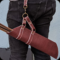 Hip mounted arrow quiver.  Burgandy with a visible white edge and brass hardware.